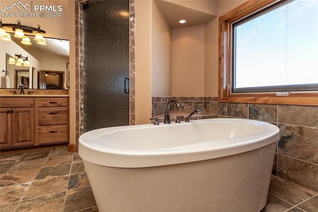 bathroom featuring tile walls, vanity, and separate shower and tub