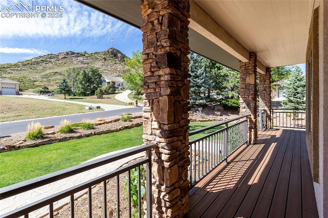 wooden deck with a mountain view, a porch, and a yard