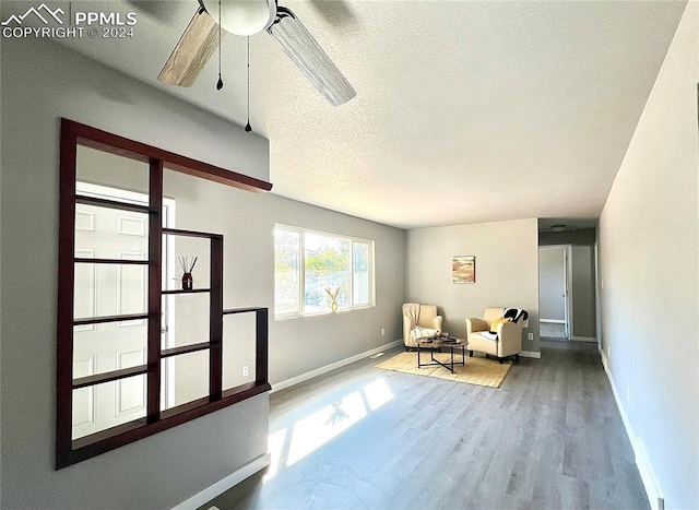 sitting room with wood-type flooring, a textured ceiling, and ceiling fan