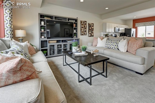 carpeted living room with beam ceiling