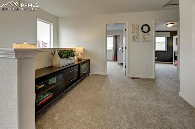 hallway with light colored carpet and a wealth of natural light