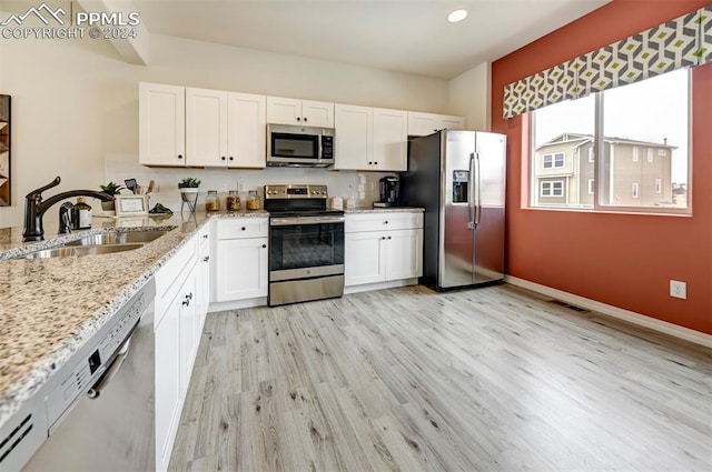 kitchen featuring light stone counters, sink, white cabinets, light hardwood / wood-style flooring, and appliances with stainless steel finishes