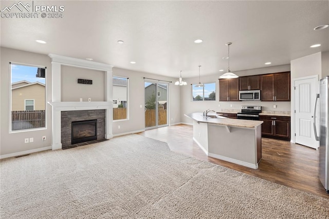 kitchen with decorative light fixtures, appliances with stainless steel finishes, a tile fireplace, and a wealth of natural light