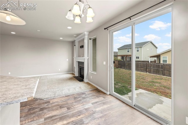 unfurnished dining area featuring hardwood / wood-style flooring, a premium fireplace, and a chandelier