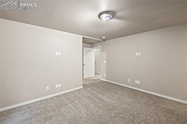 carpeted empty room featuring a textured ceiling