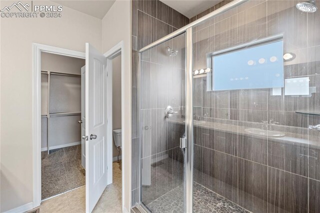 bathroom featuring tile patterned floors, a shower with shower door, and toilet