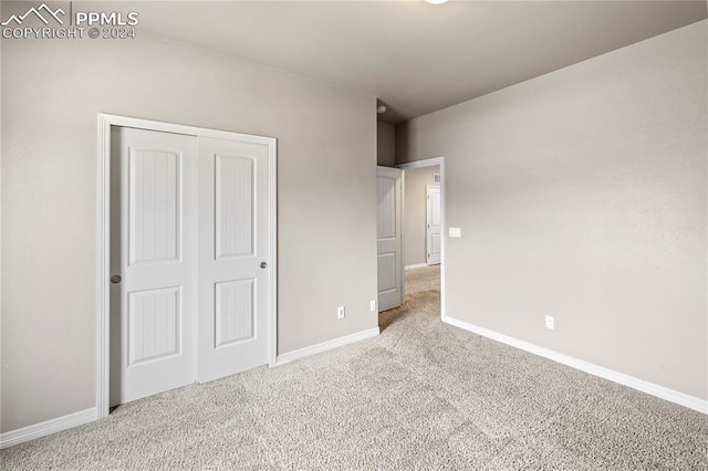 unfurnished bedroom with light carpet and a closet