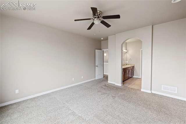 unfurnished bedroom with ceiling fan, light colored carpet, and connected bathroom