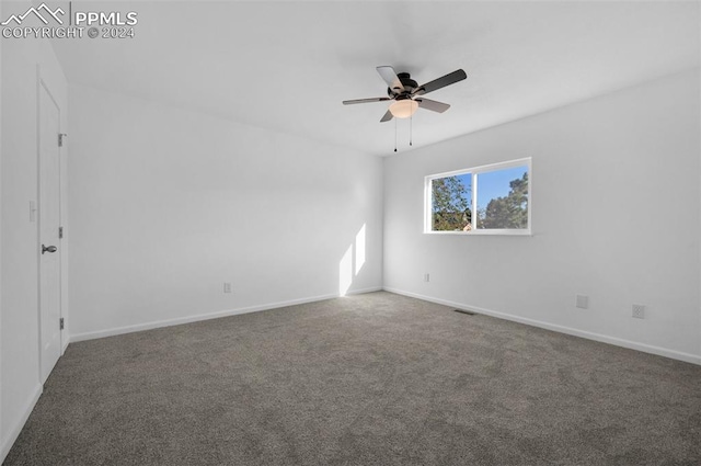 empty room with ceiling fan and dark colored carpet