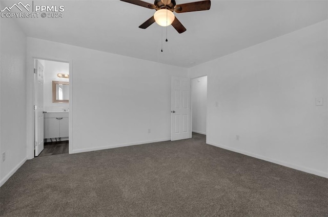 unfurnished bedroom featuring ceiling fan, ensuite bath, and dark carpet