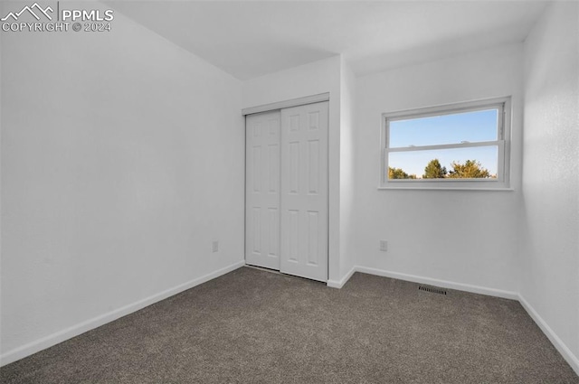 unfurnished bedroom featuring dark carpet and a closet