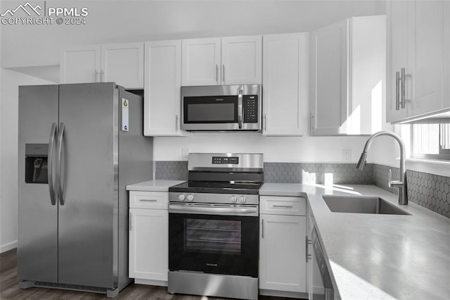 kitchen with appliances with stainless steel finishes, dark wood-type flooring, sink, and white cabinetry