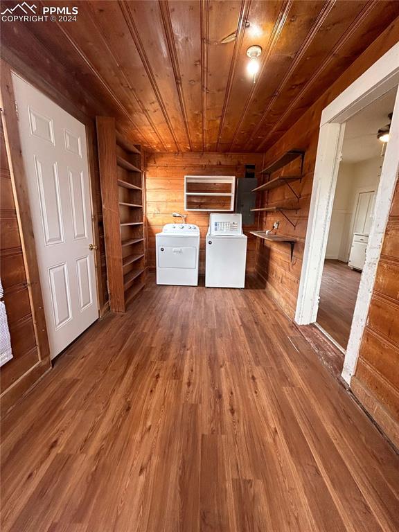 clothes washing area featuring wooden walls, dark wood-type flooring, washer and dryer, and wood ceiling