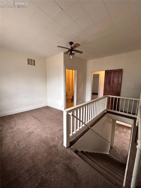 carpeted spare room featuring ceiling fan