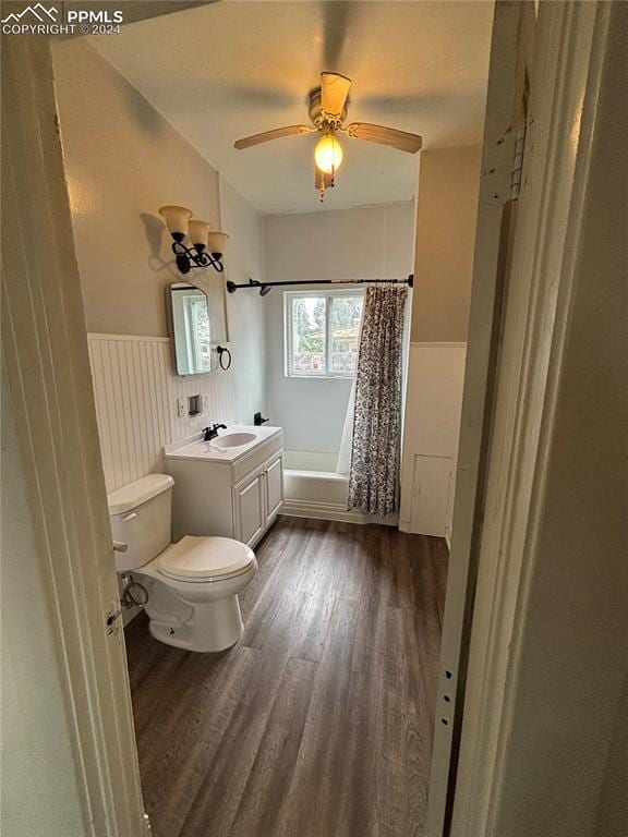 full bathroom featuring wood-type flooring, shower / tub combo with curtain, ceiling fan, vanity, and toilet