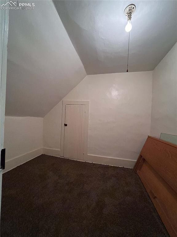 bonus room featuring vaulted ceiling and dark colored carpet