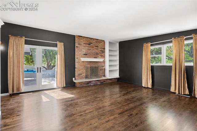 unfurnished living room featuring french doors, dark wood-type flooring, a fireplace, and built in features