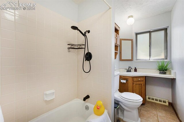 full bathroom featuring vanity, a textured ceiling, tiled shower / bath combo, toilet, and tile patterned floors