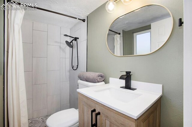 bathroom featuring a shower with curtain, vanity, toilet, and a textured ceiling