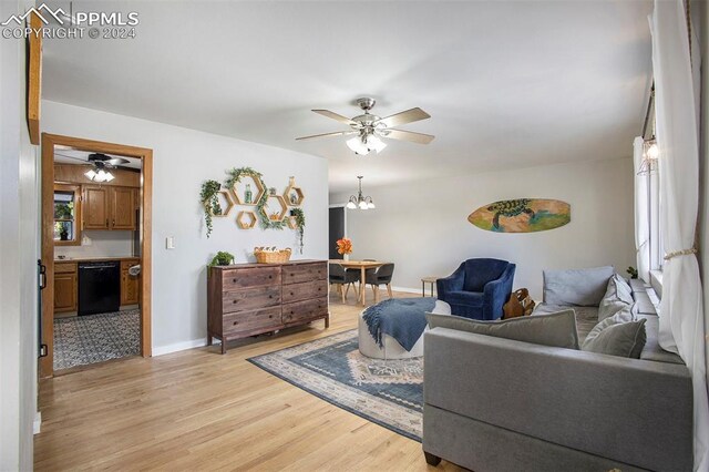 living room with ceiling fan with notable chandelier and light hardwood / wood-style flooring