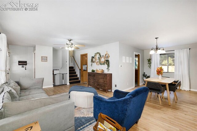 living room with ceiling fan with notable chandelier and light hardwood / wood-style floors