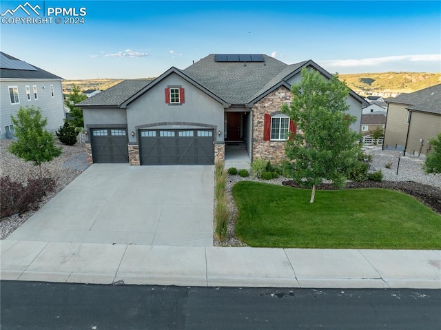 view of front of home featuring a garage, solar panels, and a front lawn