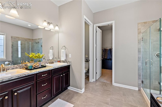 bathroom featuring vanity, toilet, a shower with door, and tile patterned floors