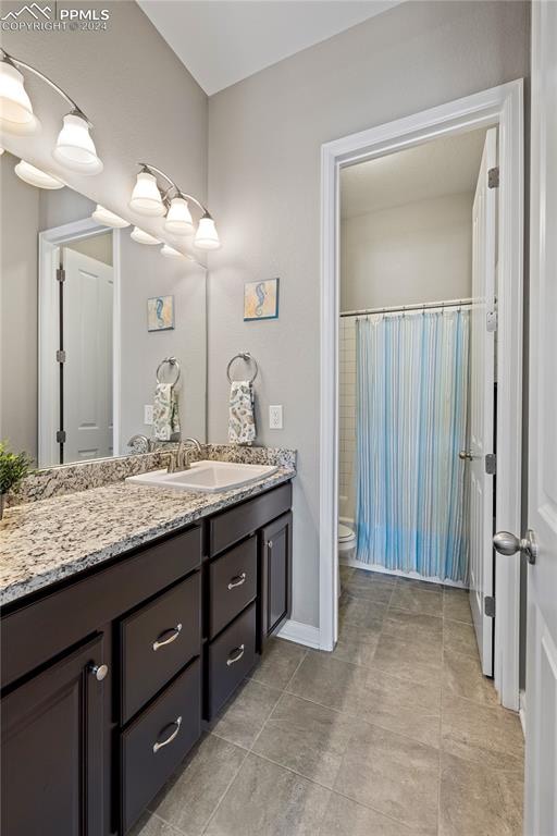 bathroom featuring curtained shower, tile patterned flooring, vanity, and toilet