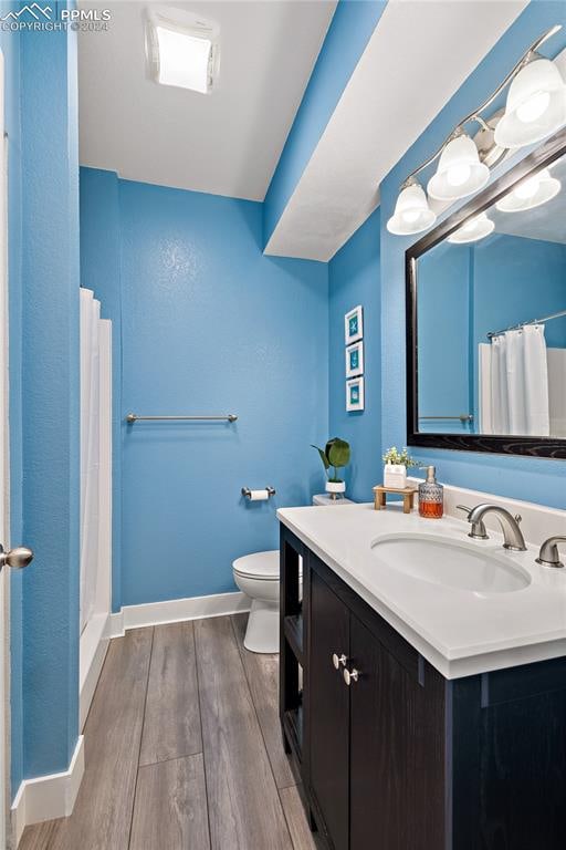 bathroom featuring walk in shower, hardwood / wood-style flooring, vanity, and toilet