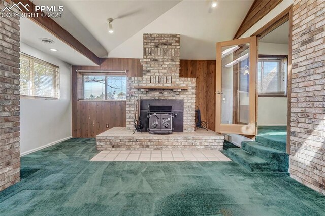 unfurnished living room with a brick fireplace, carpet flooring, wooden walls, and vaulted ceiling