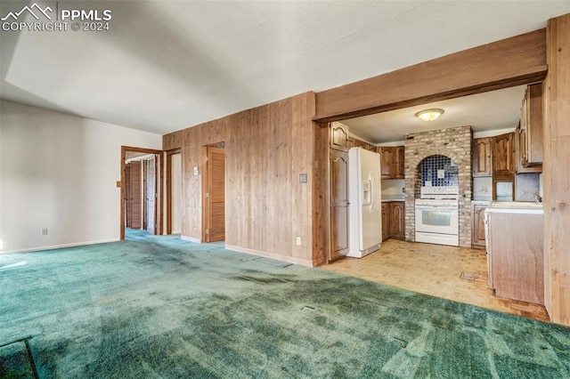 kitchen with light carpet, wooden walls, and white appliances