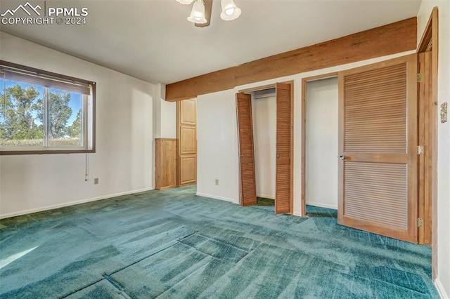 unfurnished bedroom with a notable chandelier, two closets, and carpet flooring