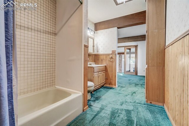 full bathroom featuring tiled shower / bath, vanity, wood walls, and toilet