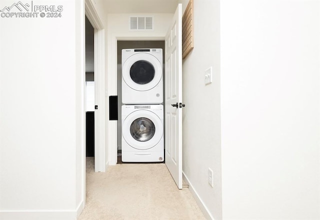 laundry room featuring stacked washer and clothes dryer and light carpet