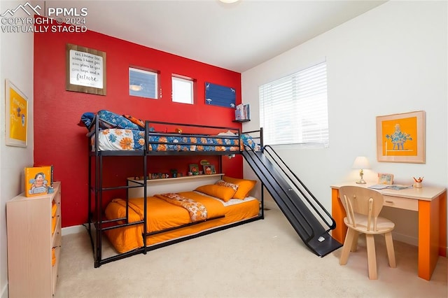 bedroom featuring light carpet, built in desk, and multiple windows