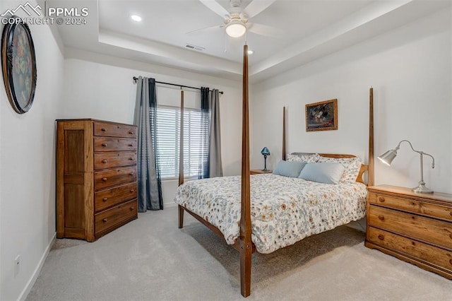 carpeted bedroom featuring ceiling fan and a raised ceiling