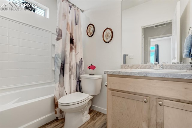 full bathroom with hardwood / wood-style floors, vanity, shower / bath combo with shower curtain, and toilet