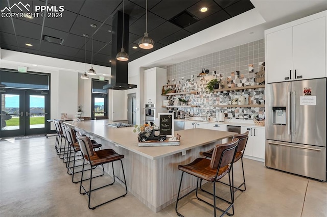 kitchen featuring decorative light fixtures, stainless steel appliances, a center island, and white cabinetry