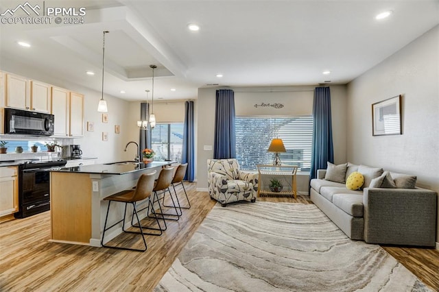 kitchen featuring a center island with sink, a breakfast bar area, black appliances, and a healthy amount of sunlight