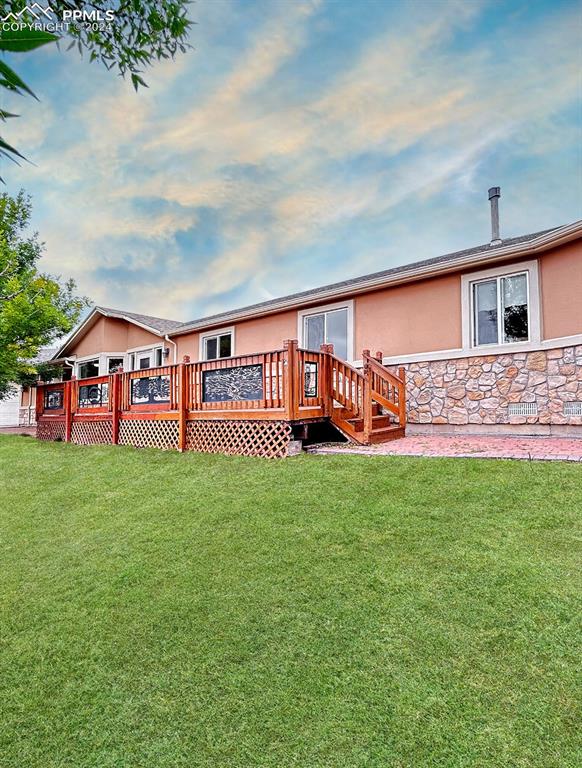 back of property with a wooden deck and a yard