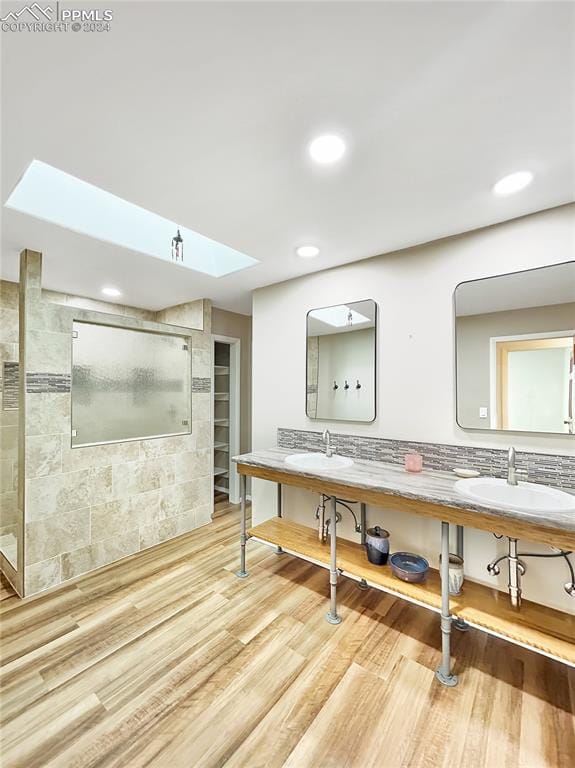 bathroom featuring decorative backsplash, wood-type flooring, walk in shower, and vanity