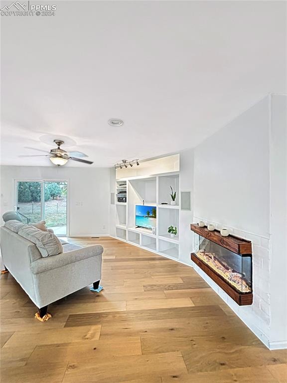 living room with light hardwood / wood-style floors, ceiling fan, and track lighting