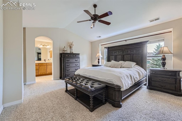 bedroom with ceiling fan, ensuite bathroom, light carpet, and vaulted ceiling