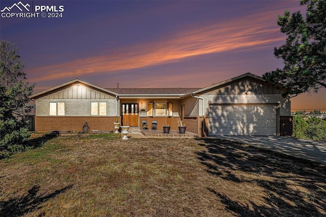 single story home with a lawn, covered porch, and a garage