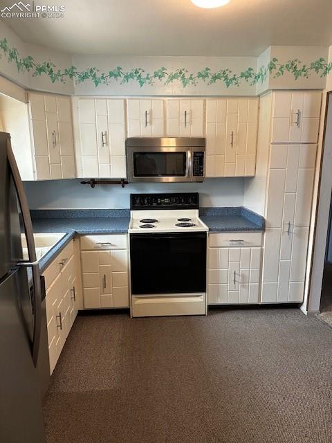 kitchen featuring dark carpet, white cabinetry, and appliances with stainless steel finishes