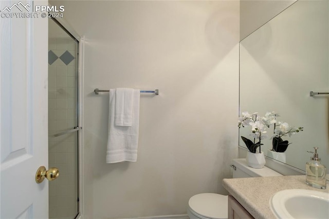 bathroom featuring a shower with door, vanity, and toilet