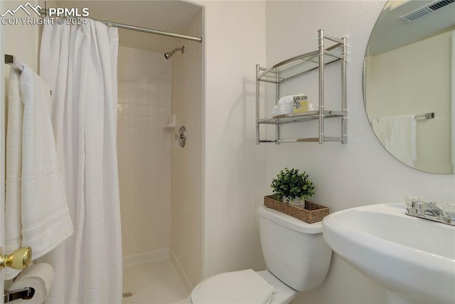 bathroom featuring a shower with shower curtain, sink, and toilet