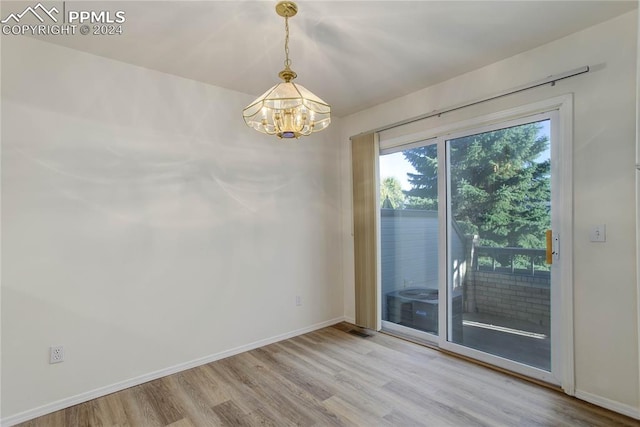 empty room featuring light hardwood / wood-style floors and a chandelier