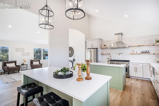 kitchen with range hood, a wealth of natural light, an island with sink, and high end appliances