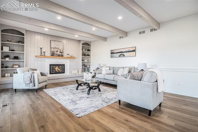 living room with beamed ceiling, built in features, and hardwood / wood-style flooring